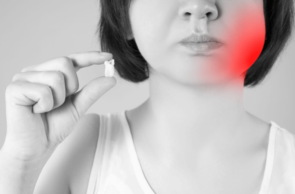 A woman has her tooth extracted due to pain. Holding her extracted wisdom tooth with two fingers