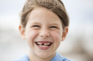 A young child with missing teeth smiling.