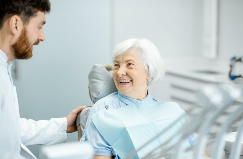 An older woman happily discusses caring for her dentures with her dentist.