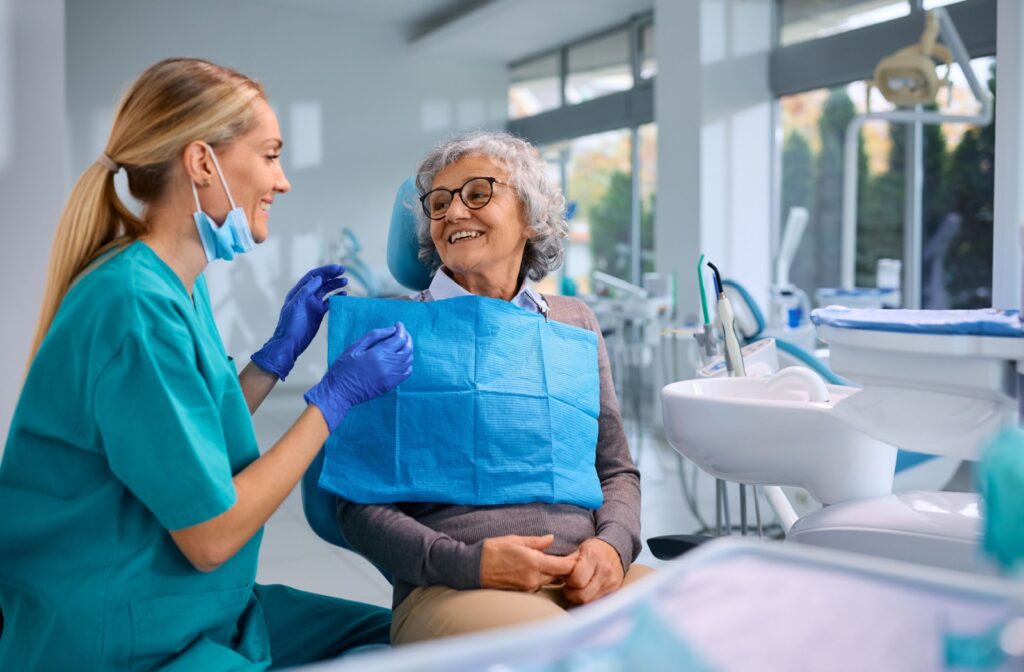 An older woman discusses laser treatment options for snoring with her dentist while sitting in a dental chair