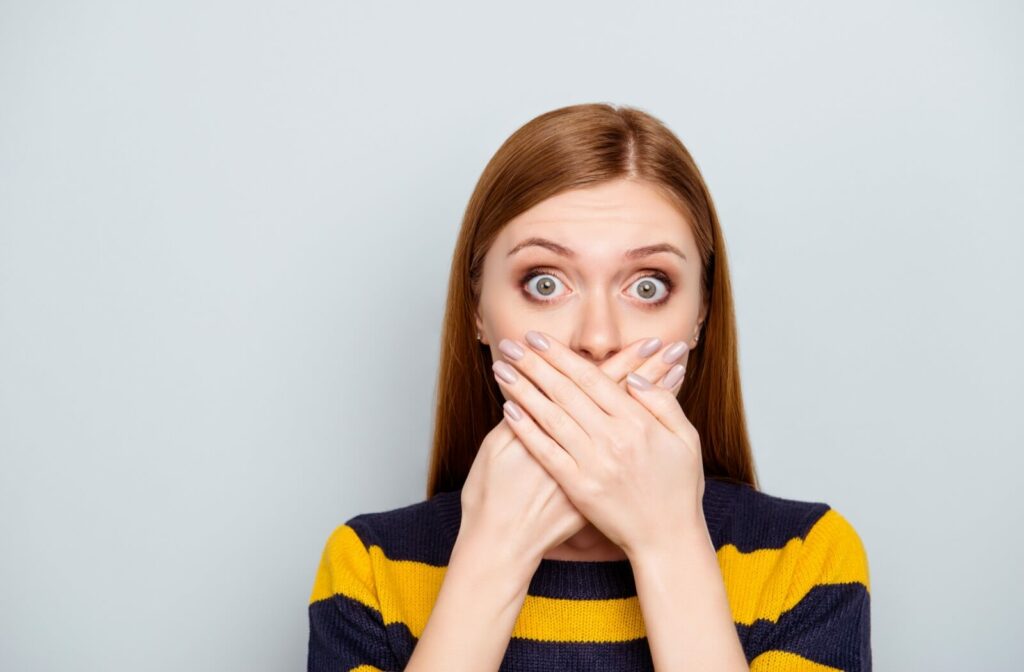 A young adult covering their mouth with their hands.