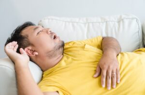 A patient sleeping with their mouth open on their couch.