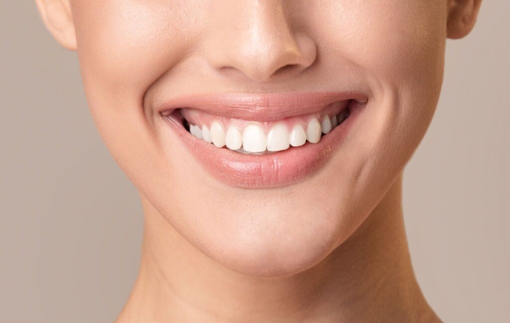 A person smiles widely after their dental cleaning, showing off their bright, white, clean teeth.